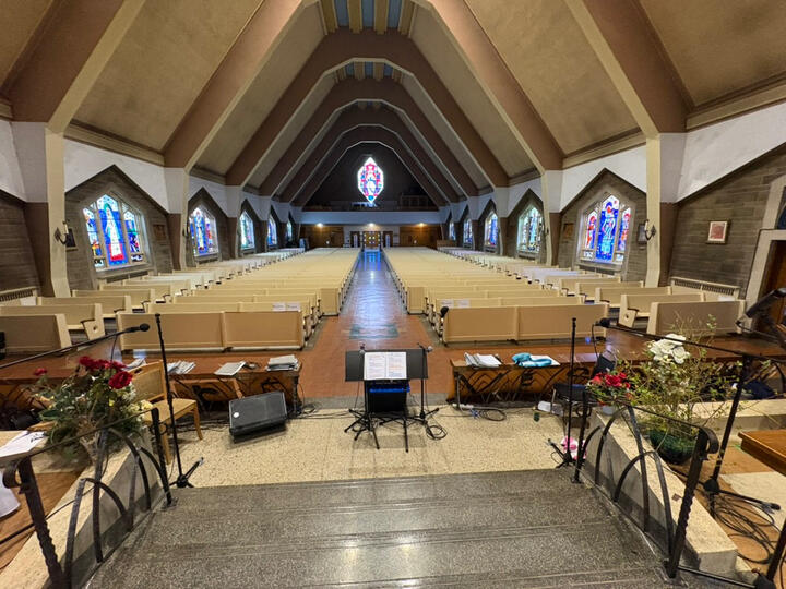 Le chœur de l'église avec des pieds de micro et des lutrins devant l'autel.